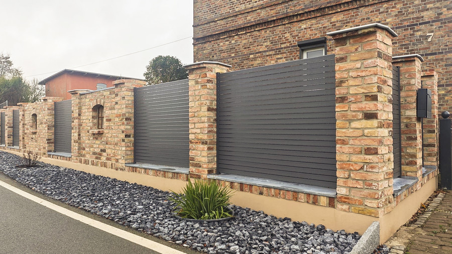 Moderner SYSTEM Sichtschutzzaun mit horizontalen Rhombusprofilen aus Aluminium in Anthrazit, integriert zwischen gemauerten Grundstückspfeilern